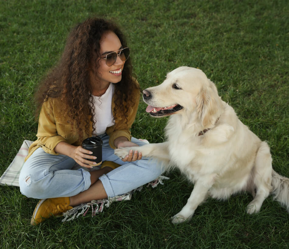 A woman sits on the grass with her dog