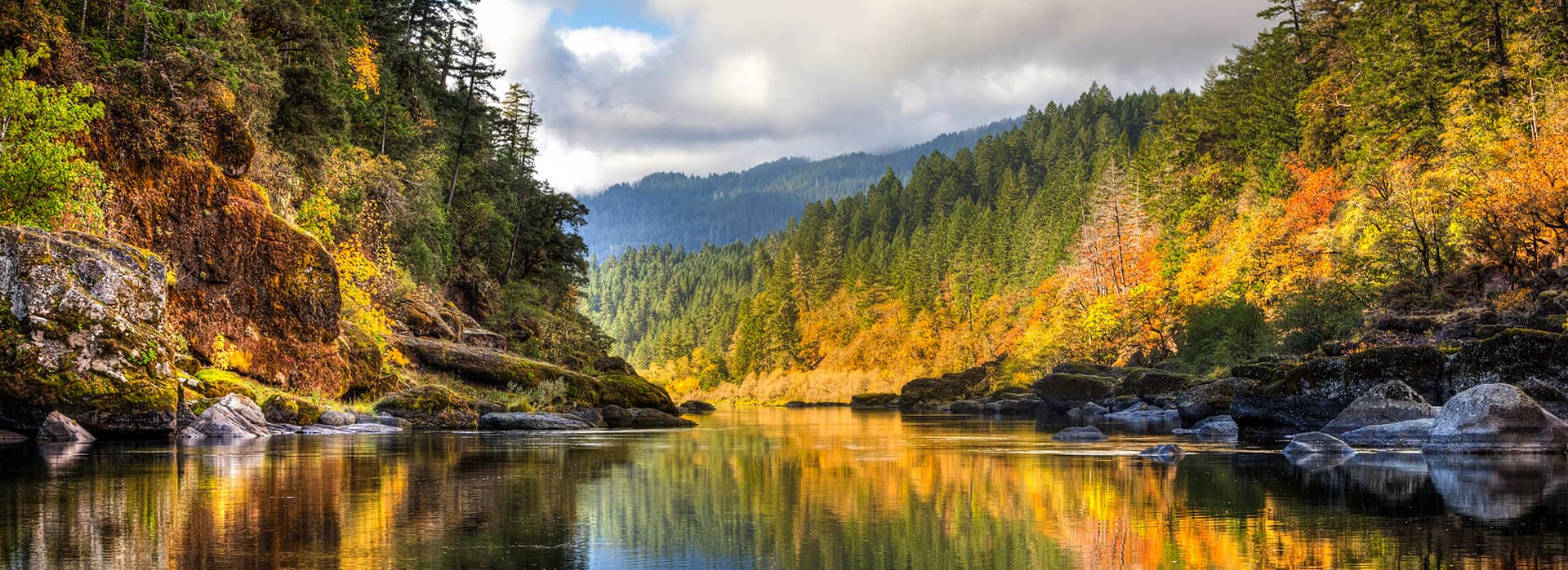 a photo of the rogue river with trees changing color in the fall